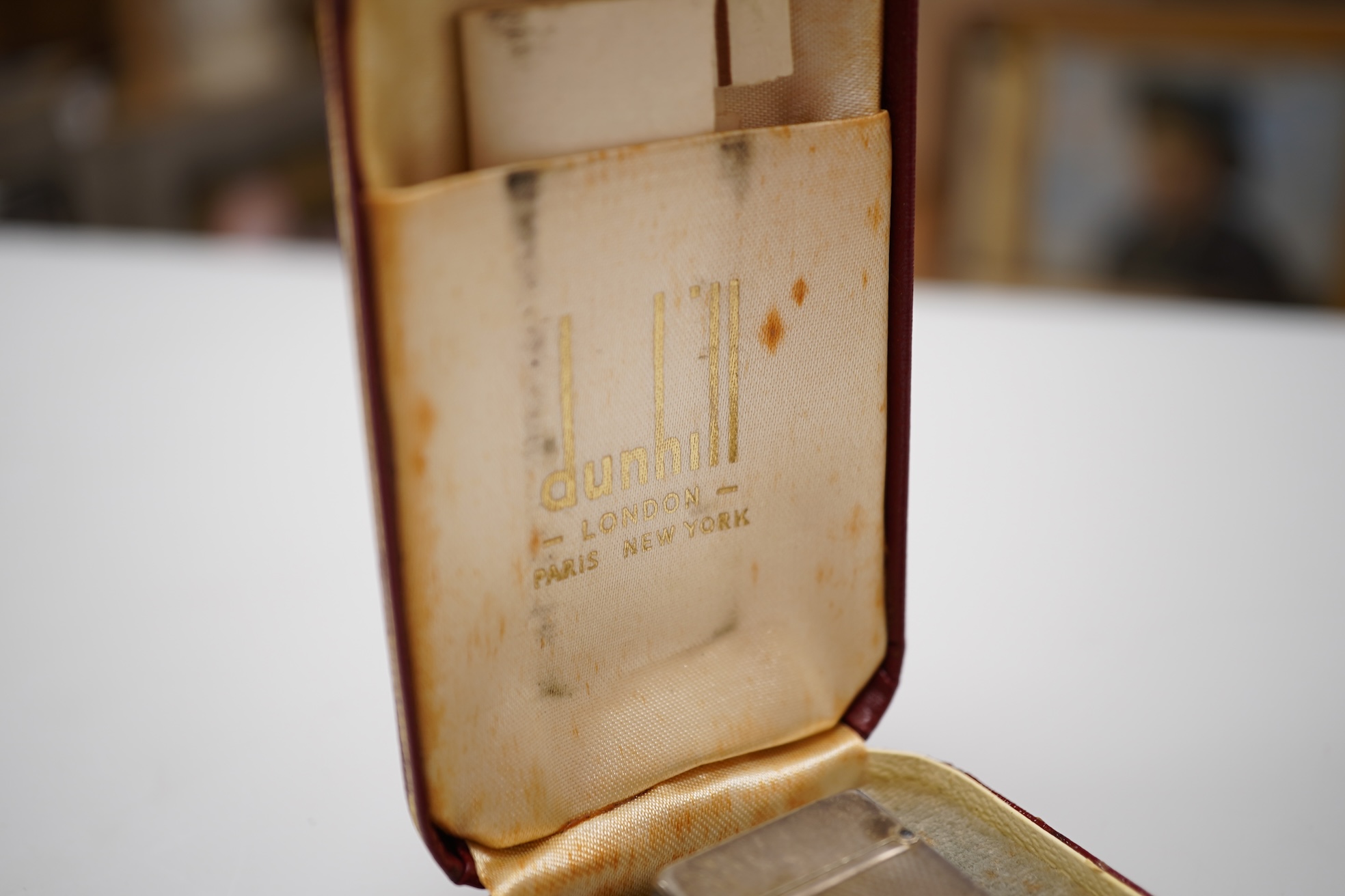 An early 20th century white metal oval locket, 40mm, on a silver chain, a silver plated Dunhill lighter, in Dunhill box, a white metal cased manual wind wrist watch and a tortoiseshell purse.